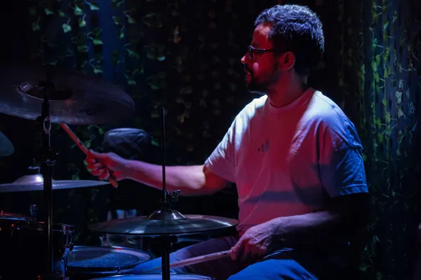 Baterista de perfil toca, com os pratos em primeiro plano