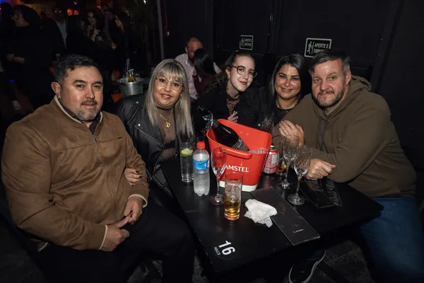 Cinco convidados sentados à mesa 16, com balde de gelo, taças e copos sobre o tampo