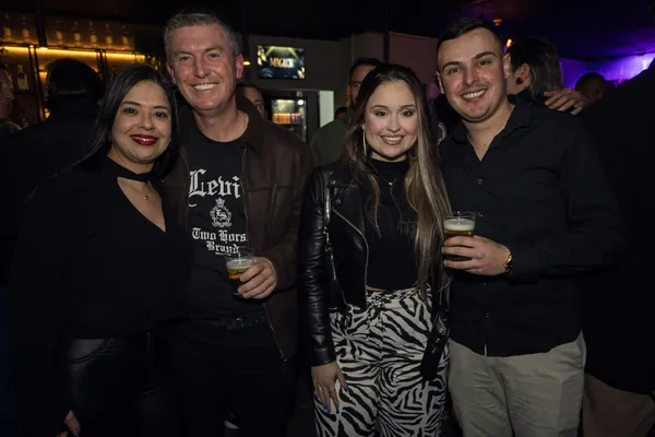 Quatro convidados posam na pista, dois deles com copos de chope